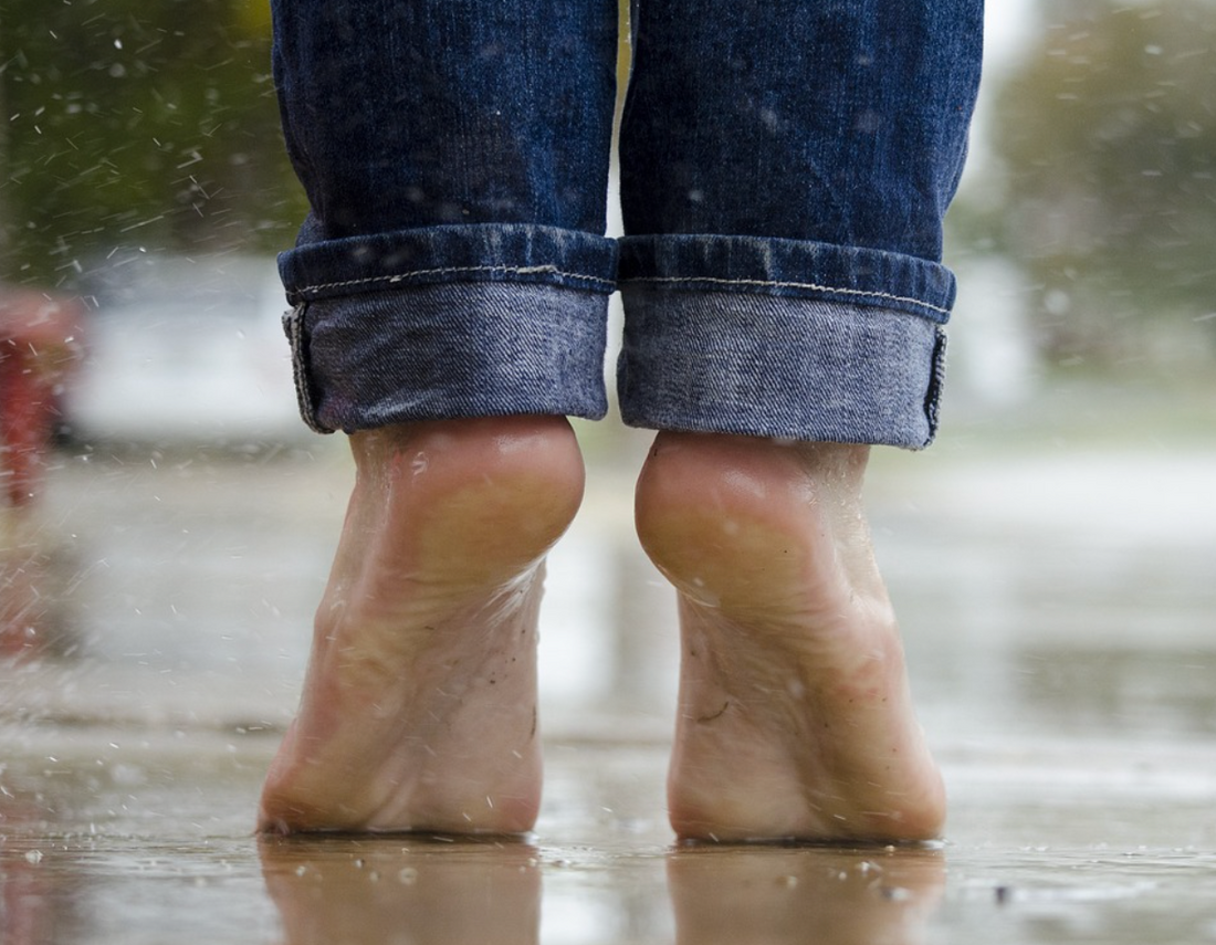 Photo of bare feet in rain not wearing Skunk Skin socks.