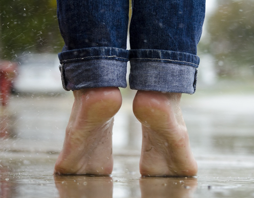 Photo of bare feet in rain not wearing Skunk Skin socks.